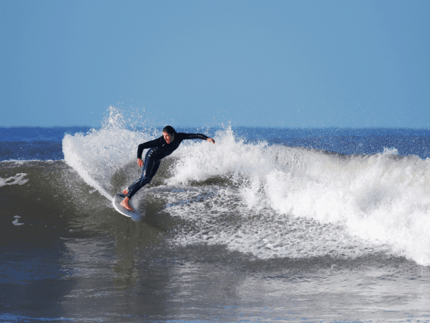Surfer riding waves near Scarborough coast North Yorkshire