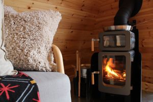 Shelter Pod interior sofa, ash bucket, and wood-burning stove, North Yorkshire glamping